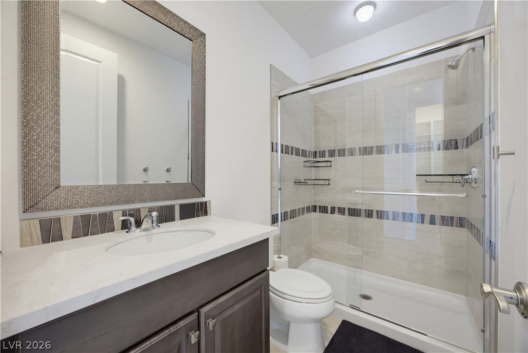 446 Bosco Di Fiore Street, Las Vegas, NV 89138 Tiled accents and a stone vanity top highlight this modern full bathroom.