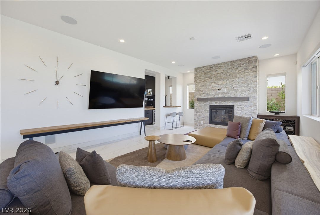 446 Bosco Di Fiore Street, Las Vegas, NV 89138 An inviting stone fireplace anchors this light-filled living area featuring sleek tile flooring.