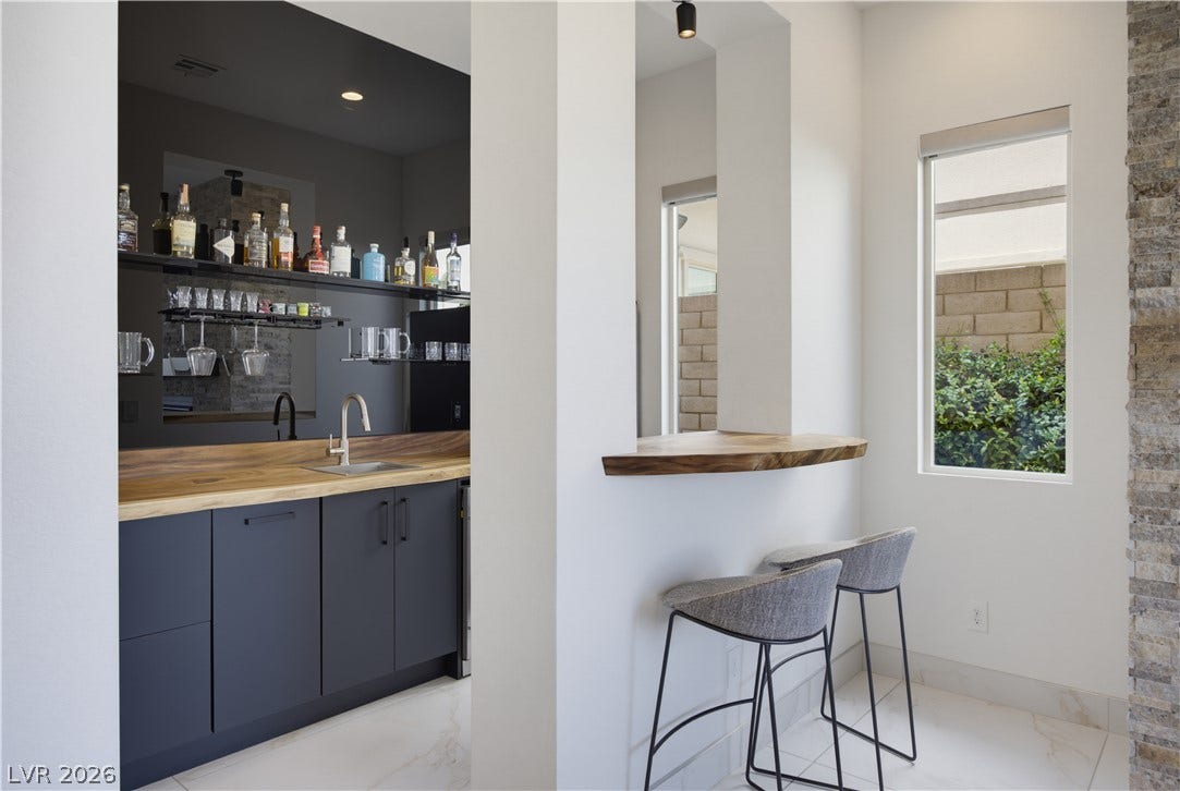 446 Bosco Di Fiore Street, Las Vegas, NV 89138 A stylish wet bar with custom wood countertops and sleek cabinetry coordinates with tiled floors.