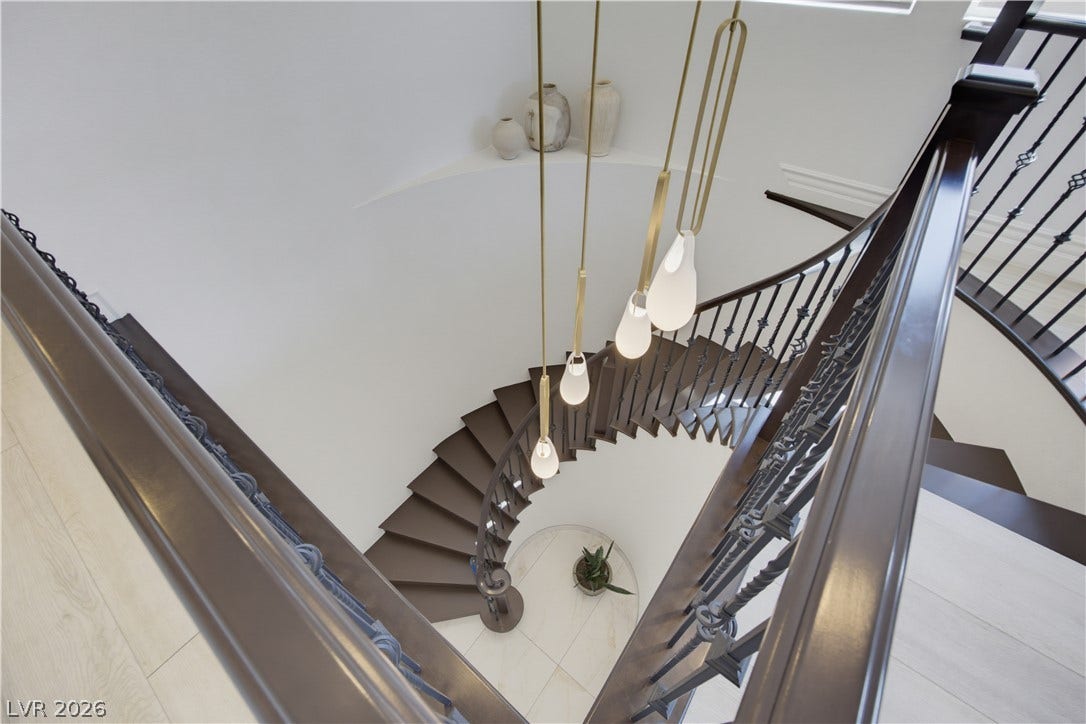 446 Bosco Di Fiore Street, Las Vegas, NV 89138 A striking curved staircase anchors this entryway with elegant wood and metal handrails.