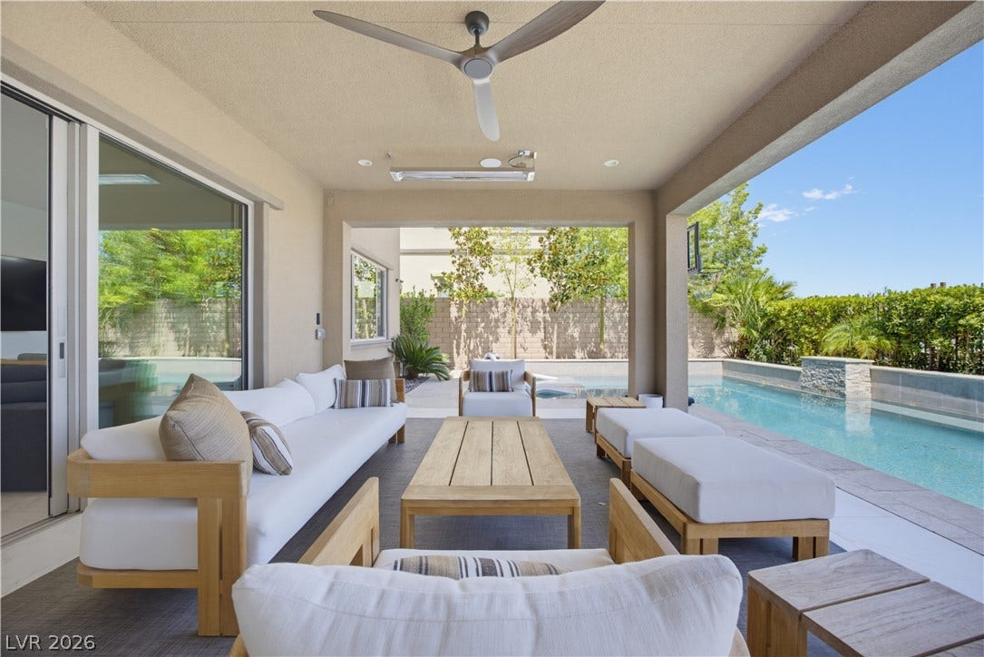 446 Bosco Di Fiore Street, Las Vegas, NV 89138 A covered patio overlooks a private pool area surrounded by lush green landscaping.
