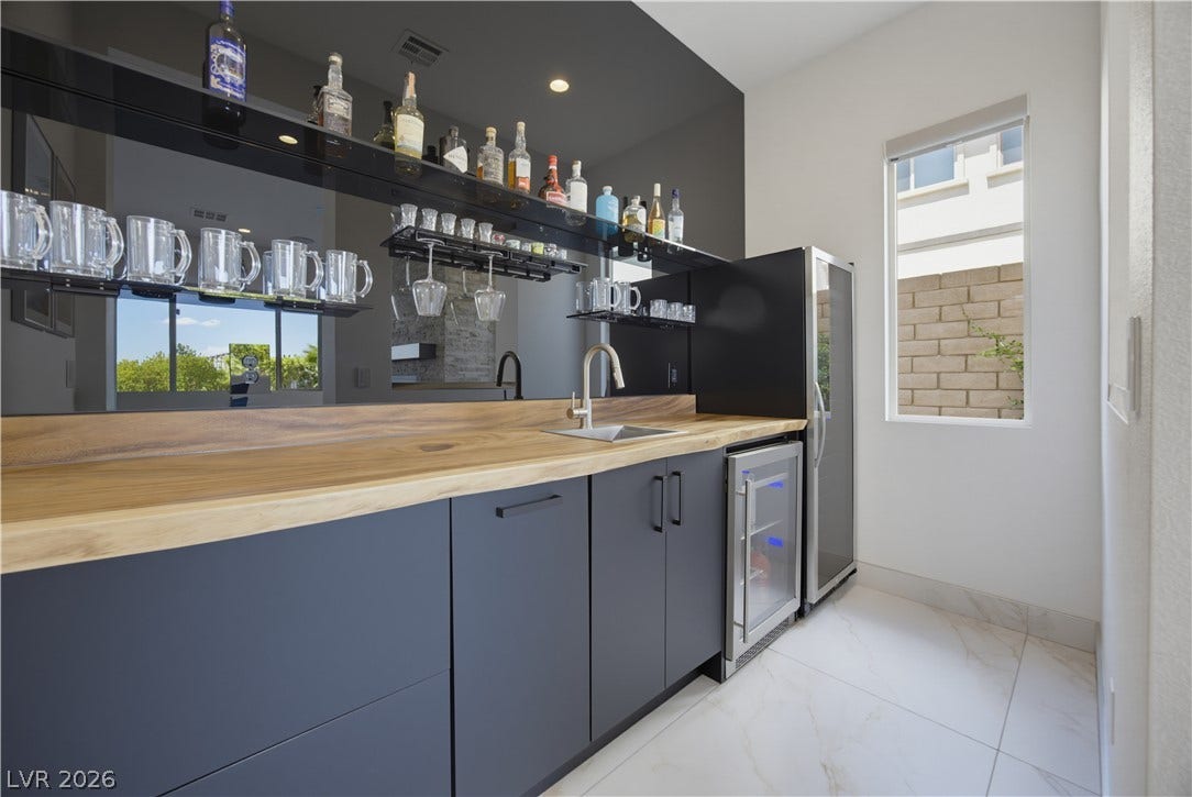 446 Bosco Di Fiore Street, Las Vegas, NV 89138 Rich wood countertops and clean cabinetry define this sleek home bar space.