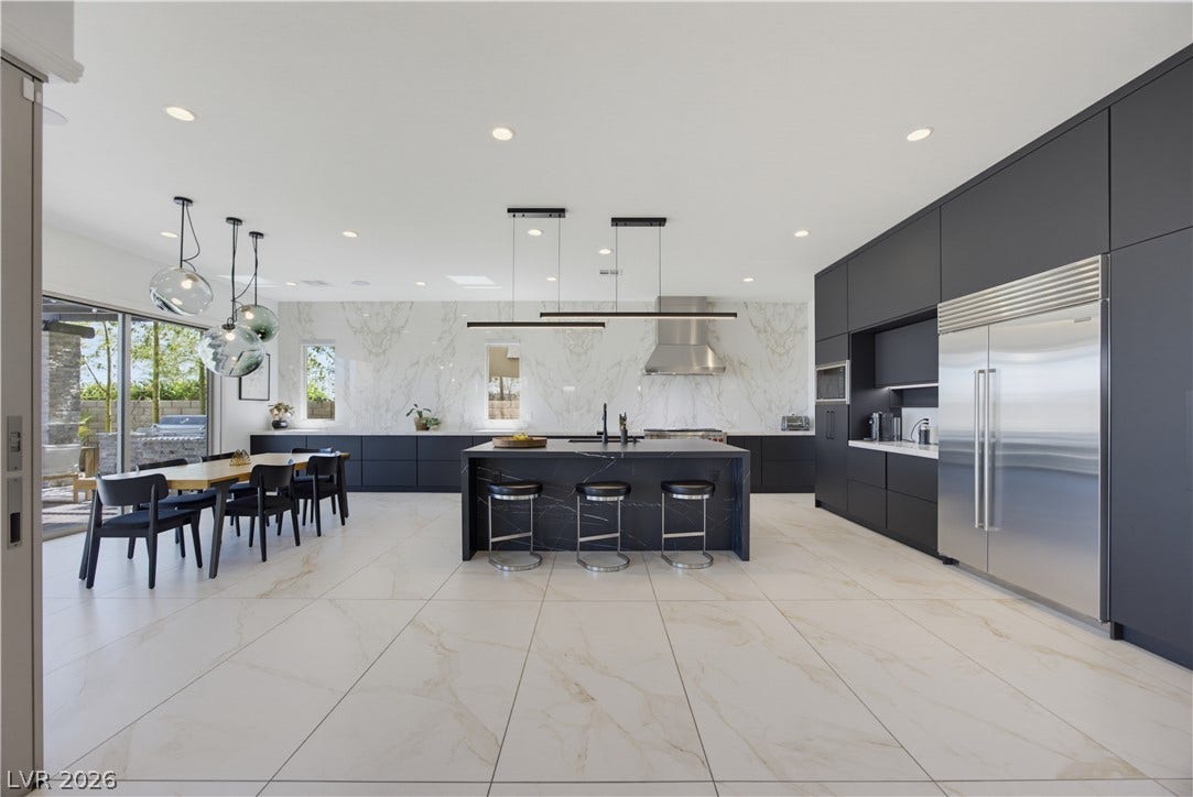 446 Bosco Di Fiore Street, Las Vegas, NV 89138 A spacious minimalist kitchen features matte black cabinetry, marble slab backsplashes, and tiled flooring.