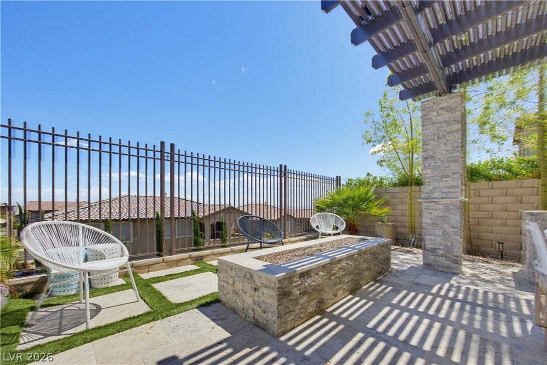 446 Bosco Di Fiore Street, Las Vegas, NV 89138 An inviting stone fire pit area sits beneath a custom pergola in this landscaped backyard.