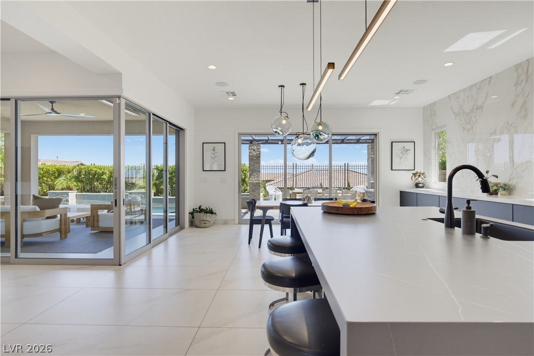 446 Bosco Di Fiore Street, Las Vegas, NV 89138 An open floorplan seamlessly connects the stone island kitchen with polished tile floors to the outdoors.