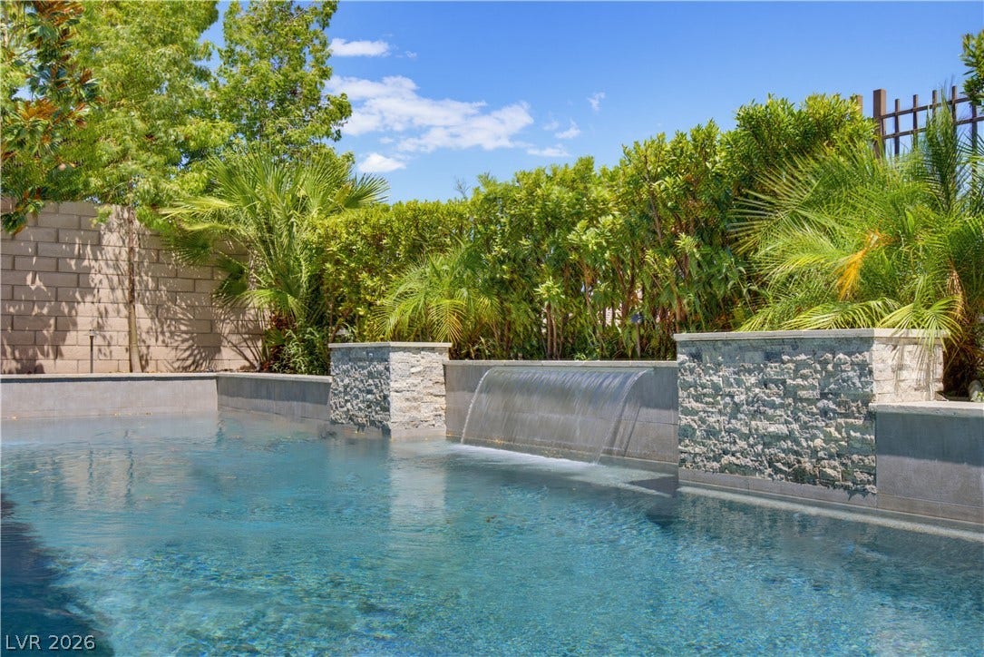 446 Bosco Di Fiore Street, Las Vegas, NV 89138 Lush tropical landscaping and stone pillars frame a pristine pool complete with a waterfall feature.