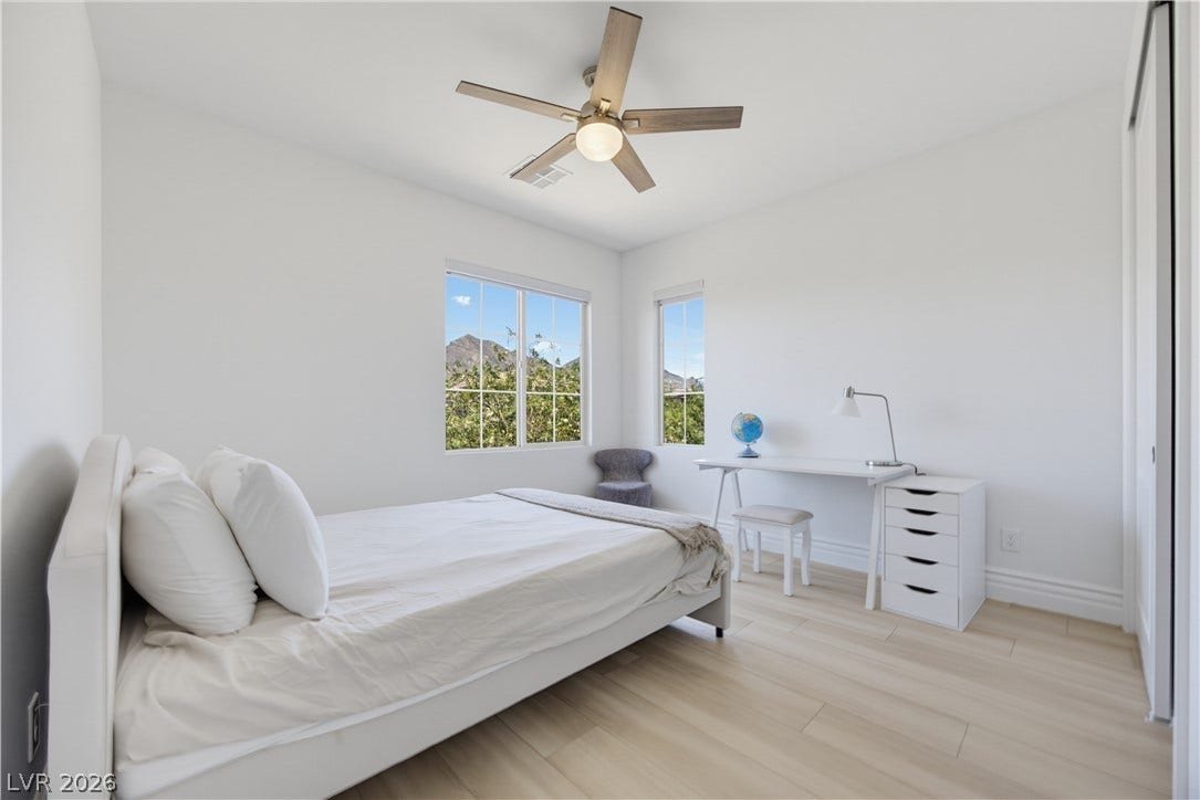 446 Bosco Di Fiore Street, Las Vegas, NV 89138 Sunlight streams through dual windows onto sleek wood-style flooring in this airy bedroom.