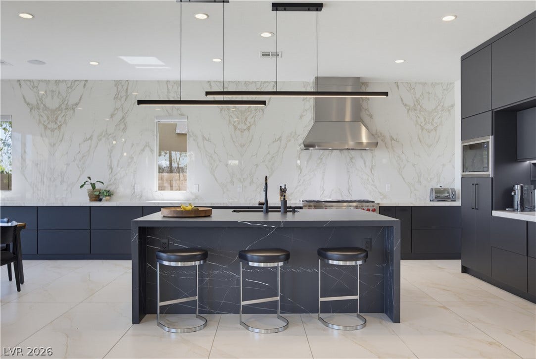446 Bosco Di Fiore Street, Las Vegas, NV 89138 A minimalist kitchen showcases sleek modern cabinetry alongside an extensive marble-patterned backsplash.
