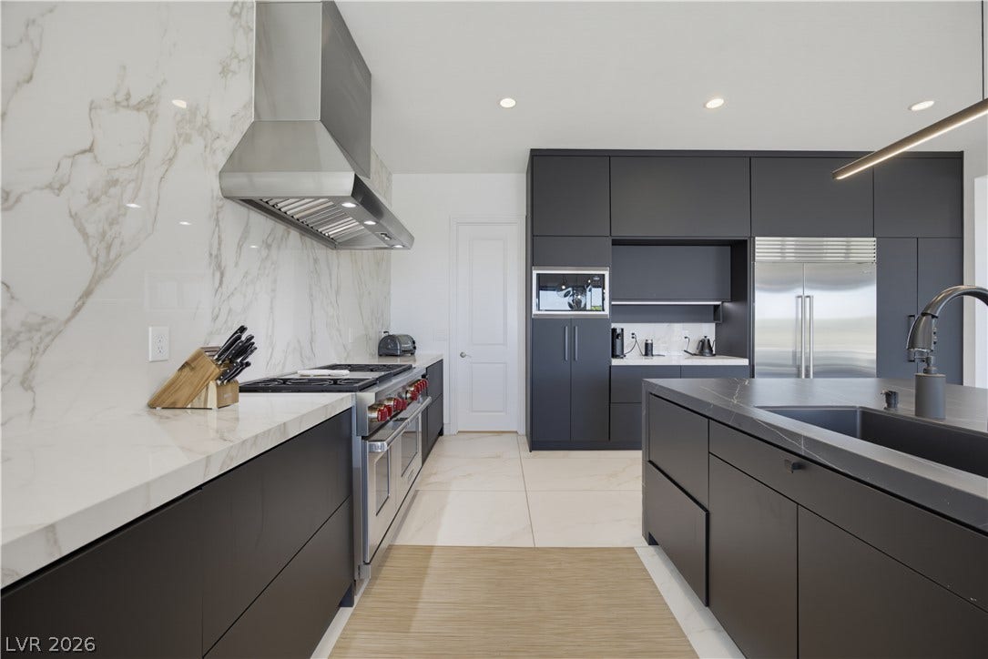 446 Bosco Di Fiore Street, Las Vegas, NV 89138 Sleek dark cabinetry and stone countertops anchor this minimalist gourmet kitchen.