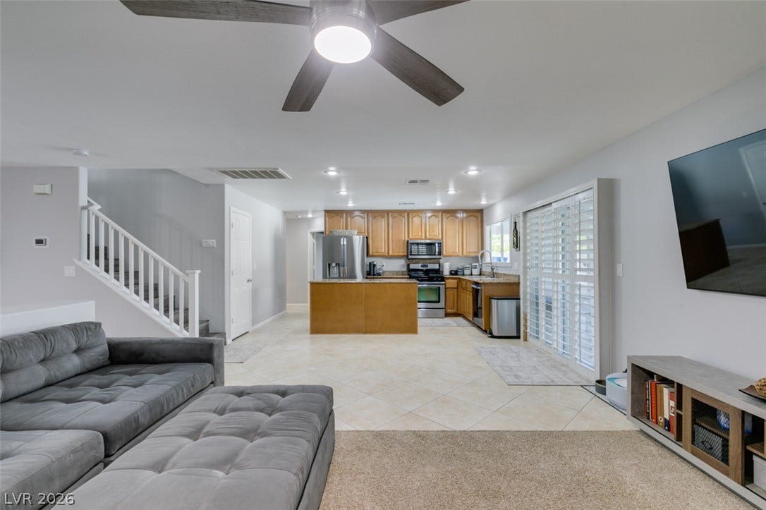 236 Fox Lake Avenue, Las Vegas, NV 89148 An open layout connects the tiled kitchen and carpeted living space near a central staircase.
