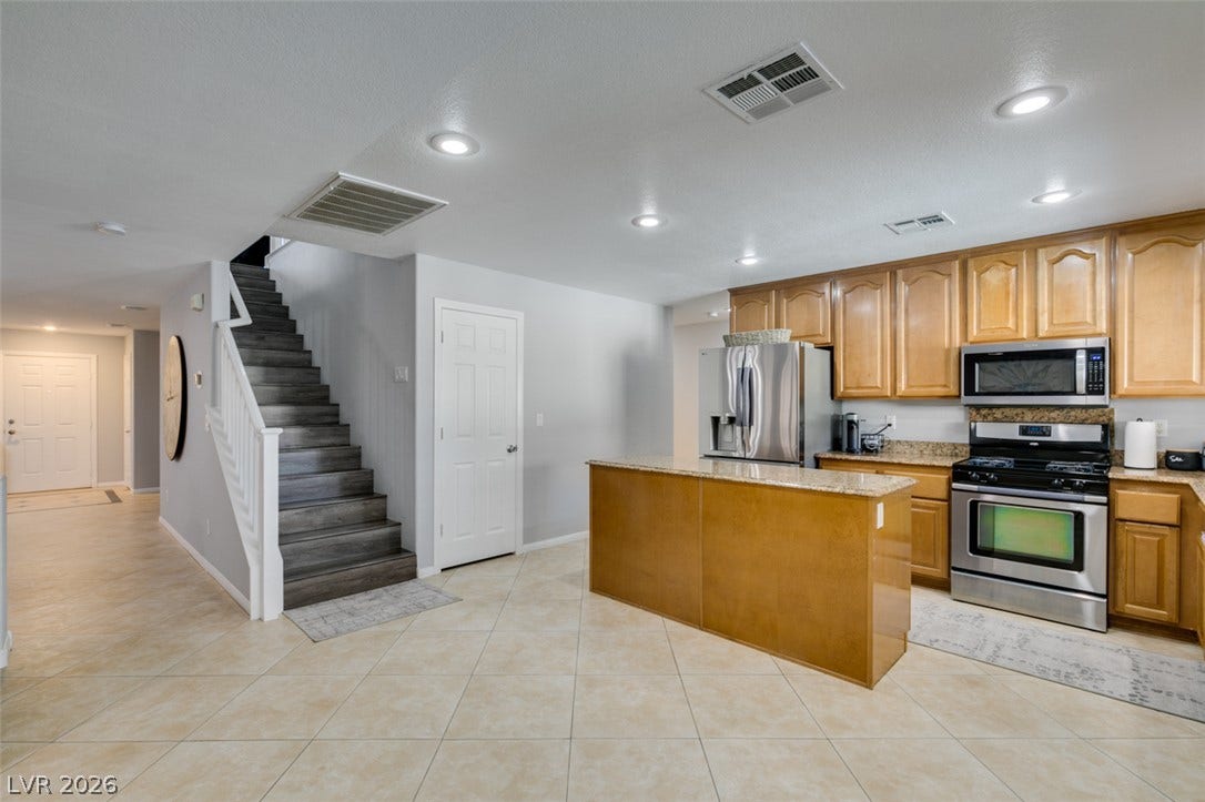 236 Fox Lake Avenue, Las Vegas, NV 89148 Tiled flooring and wood cabinetry define this open kitchen adjacent to the main staircase.