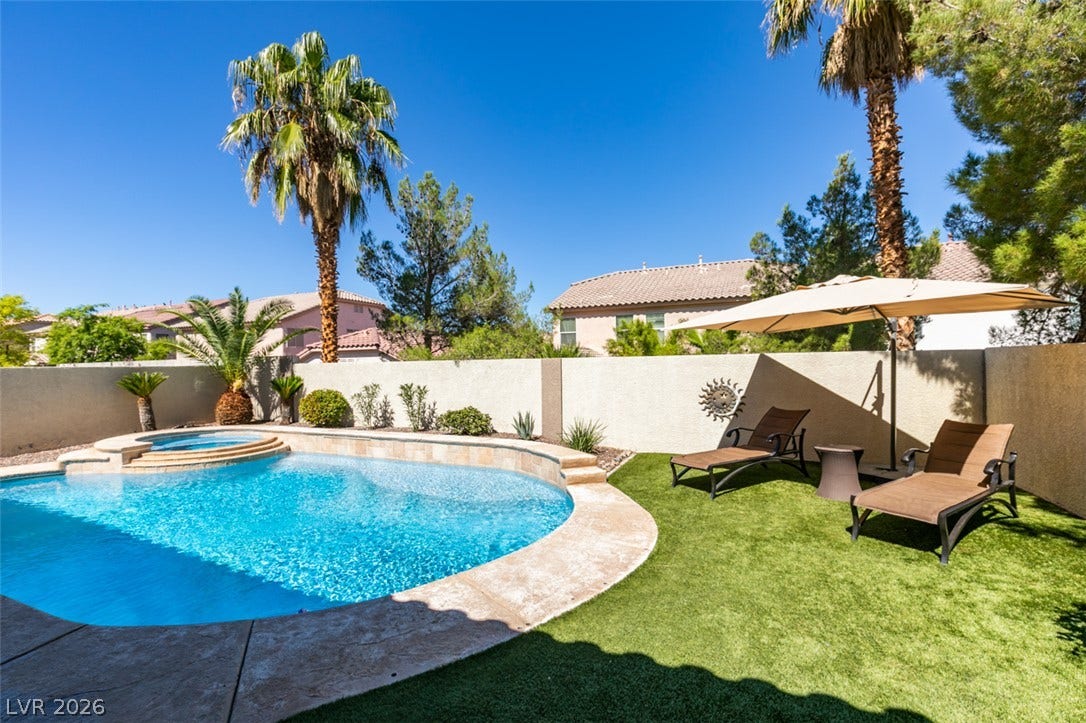 236 Fox Lake Avenue, Las Vegas, NV 89148 An inviting backyard oasis features a shimmering custom pool alongside a manicured lawn.