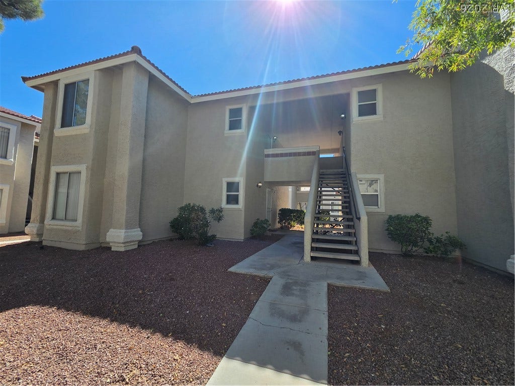 7300 Pirates Cove Road, #2060, Las Vegas, NV 89145 A concrete walkway leads past stucco walls and exterior stairs under clear desert skies.