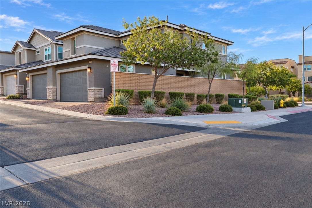 A modern corner townhouse features sleek stucco exteriors, integrated garages, and low-maintenance desert landscaping.