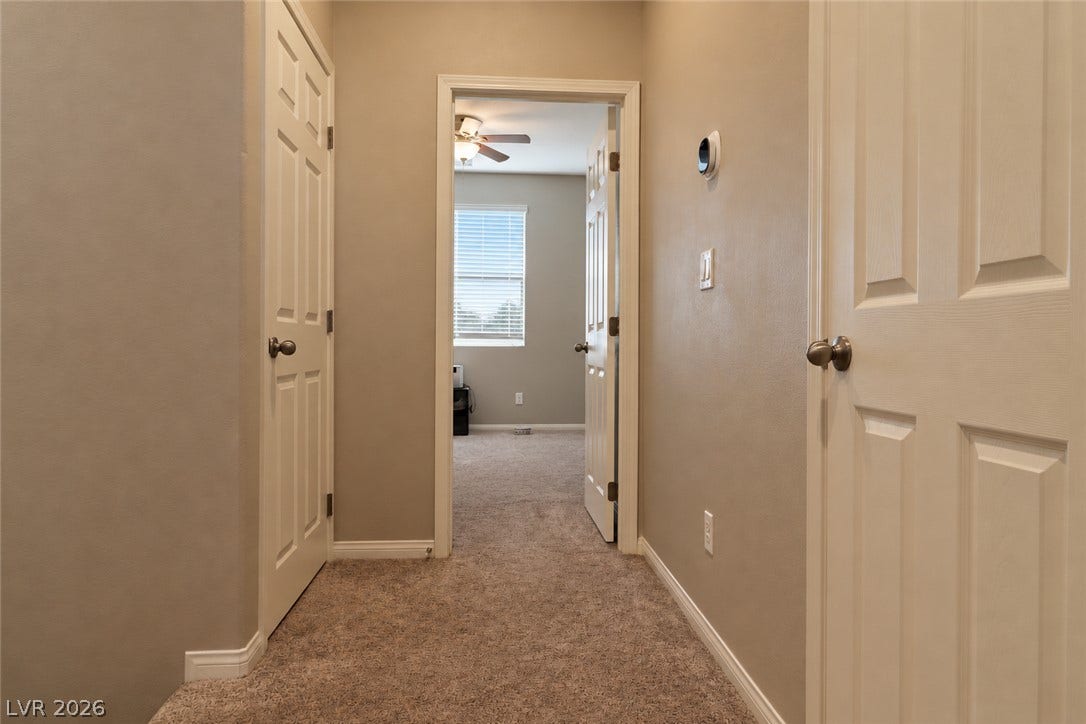 Carpeted flooring leads through a hallway toward an adjacent bedroom space.