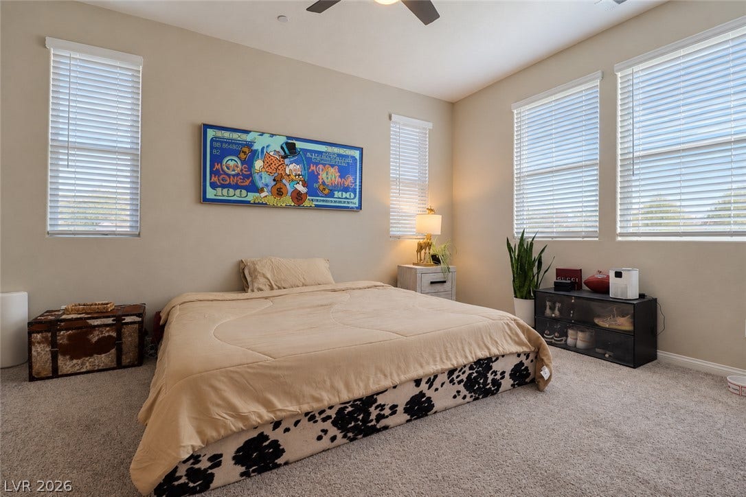Plentiful windows draw natural light into this comfortable bedroom with soft carpet flooring.