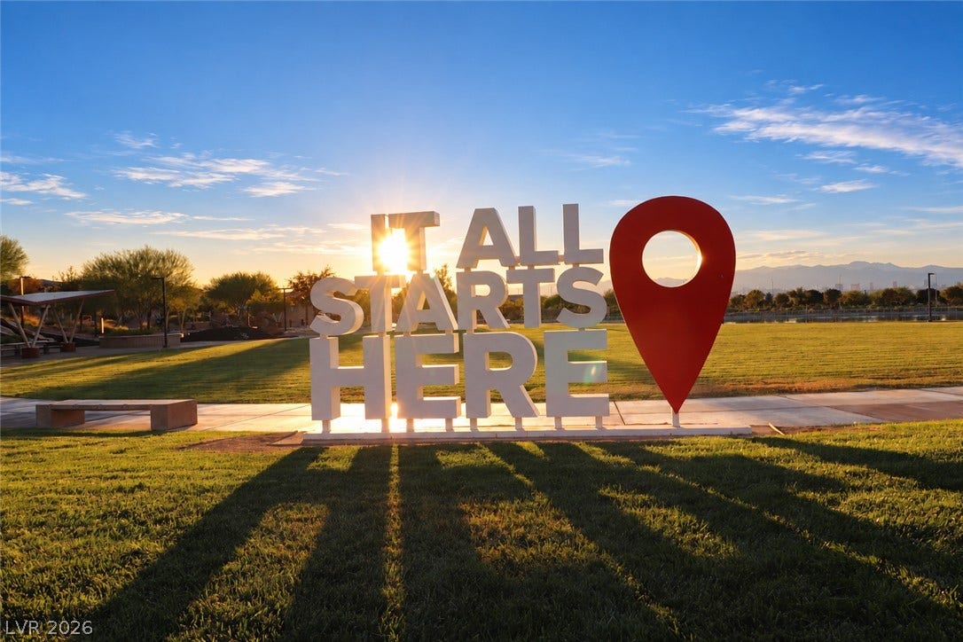 Lush manicured park grounds surround paved walking paths beneath a clear desert sky.