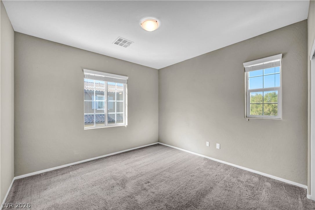 8577 Insignia Avenue, #101, Las Vegas, NV 89178 Multi-pane windows draw natural light onto plush carpeting in a serene, neutral space.