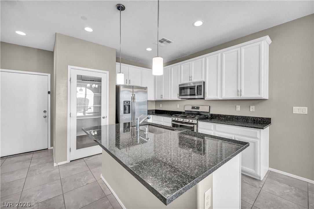 8577 Insignia Avenue, #101, Las Vegas, NV 89178 Granite countertops paired with white cabinetry anchor this modern culinary workspace.