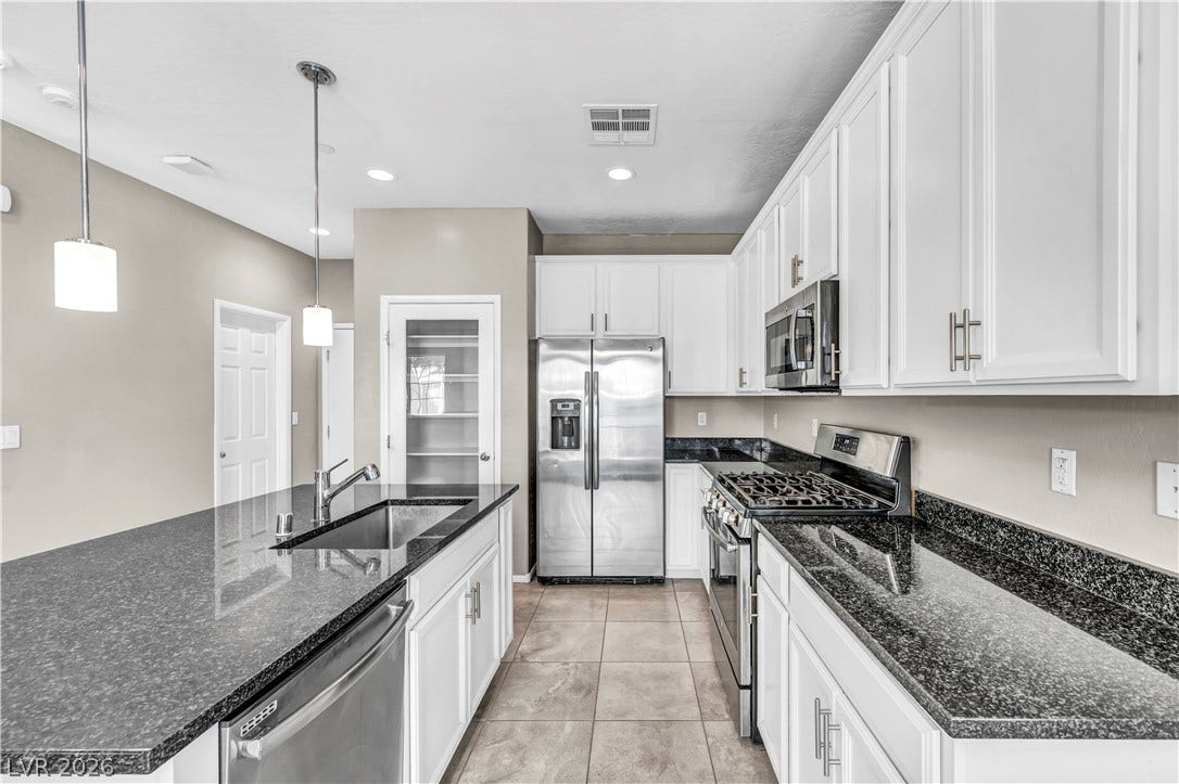 8577 Insignia Avenue, #101, Las Vegas, NV 89178 Granite countertops and crisp white cabinetry define this beautifully updated cooking space.