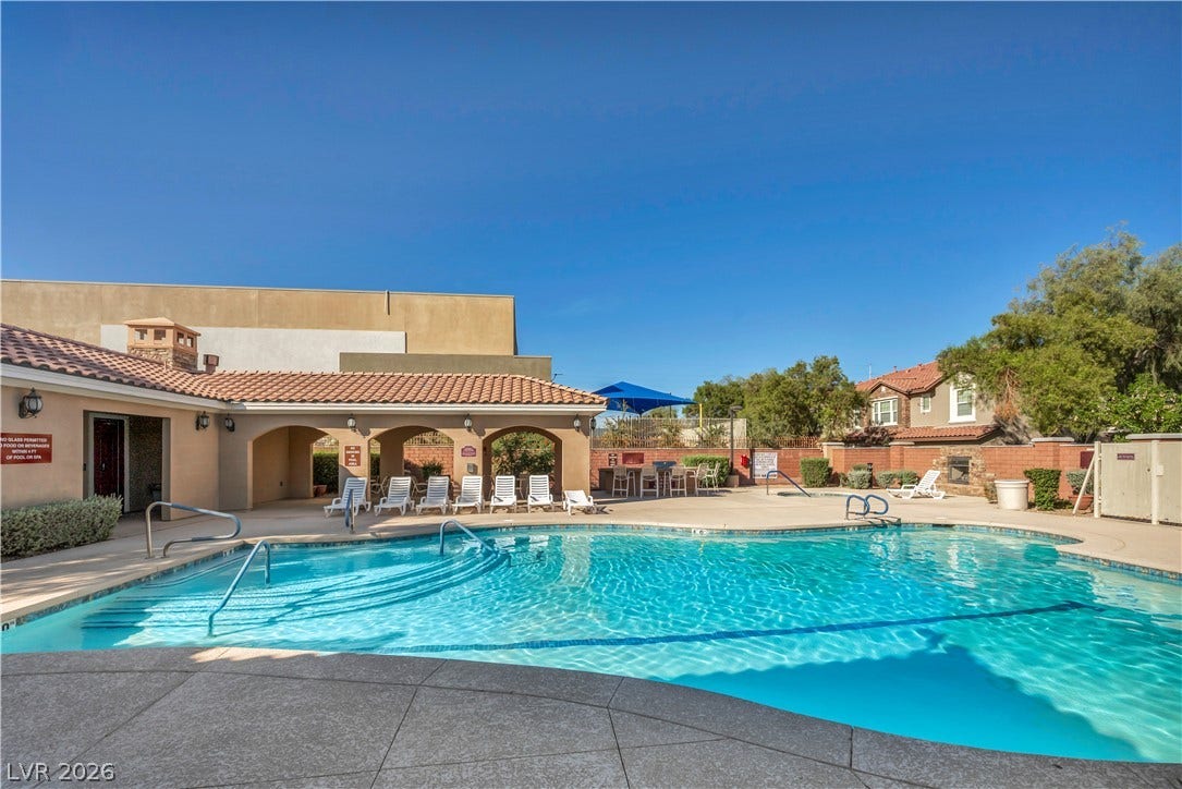 8577 Insignia Avenue, #101, Las Vegas, NV 89178 An inviting swimming pool area sits surrounded by classic tile-roof architecture under clear blue skies.