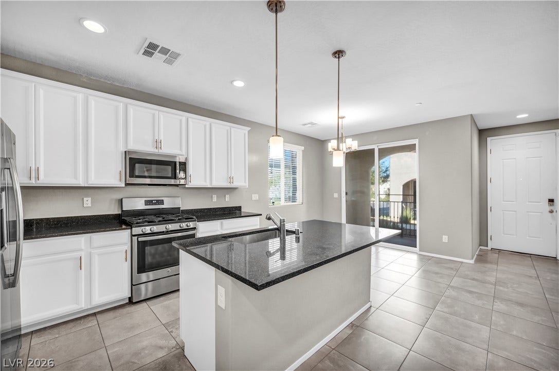 8577 Insignia Avenue, #101, Las Vegas, NV 89178 Gleaming stone countertops and a central island ground this open modern cooking space.
