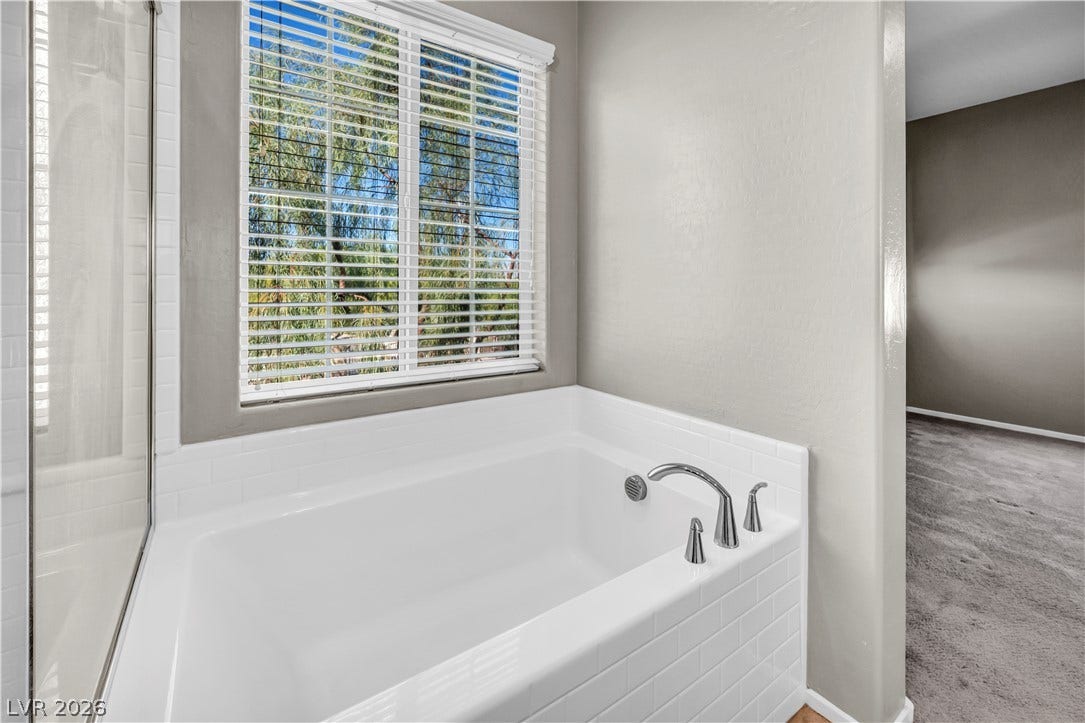 8577 Insignia Avenue, #101, Las Vegas, NV 89178 A deep soaking tub sits beneath a large window clad in crisp white tile.