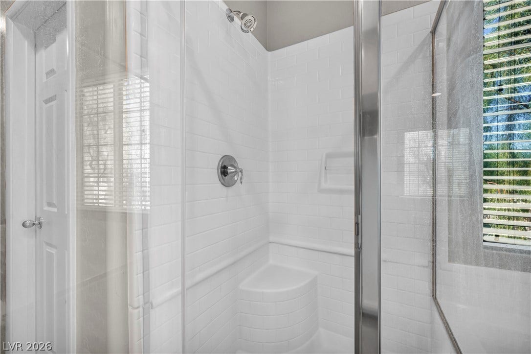8577 Insignia Avenue, #101, Las Vegas, NV 89178 Crisp white subway tiles line the walk-in shower featuring a built-in bench and glass enclosure.