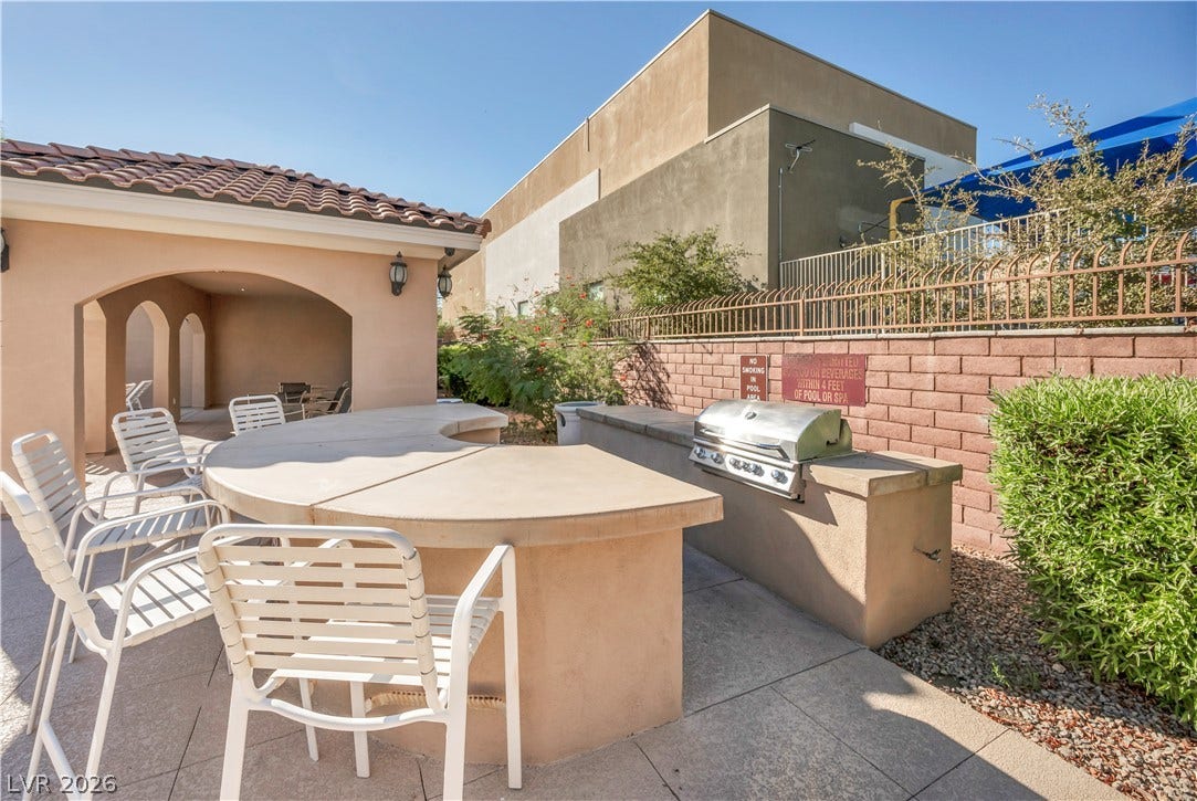 8577 Insignia Avenue, #101, Las Vegas, NV 89178 An outdoor kitchen features a built-in barbecue grill alongside a curved concrete service bar.