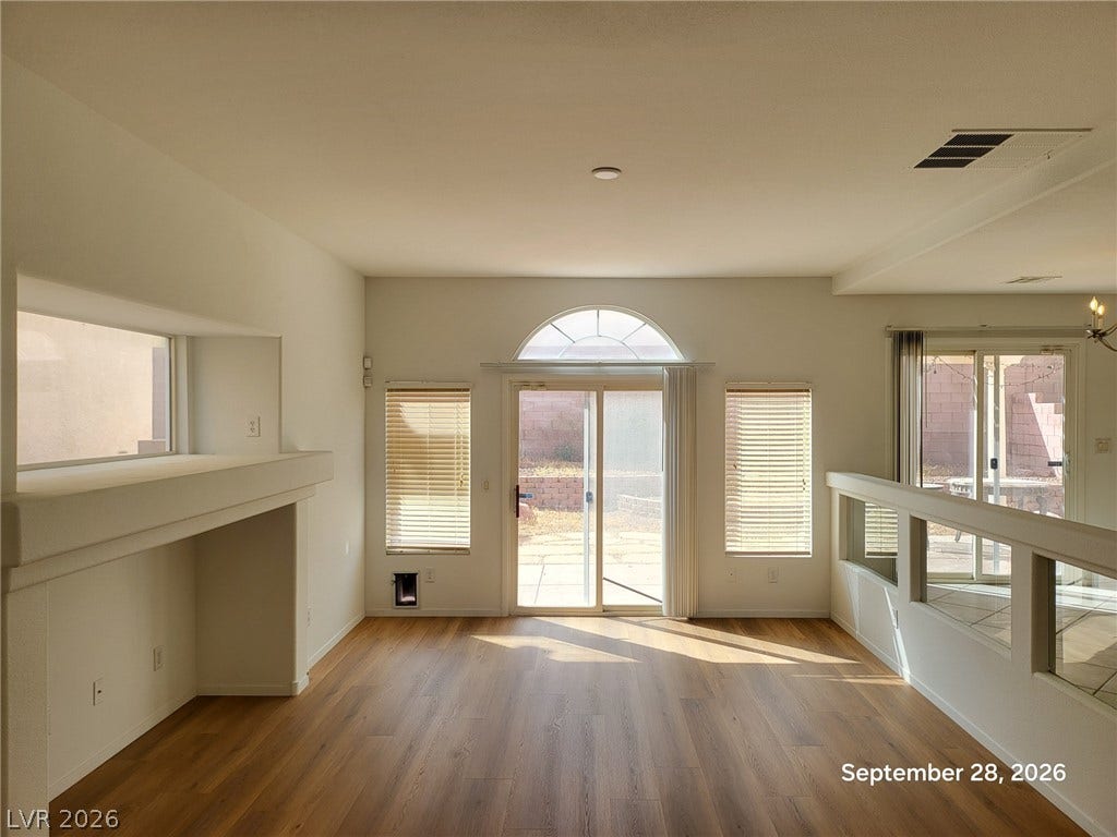 7619 Good Fortune Court, Las Vegas, NV 89139 Sunlight streams across the wood floors of a welcoming living room featuring arched glass doors.