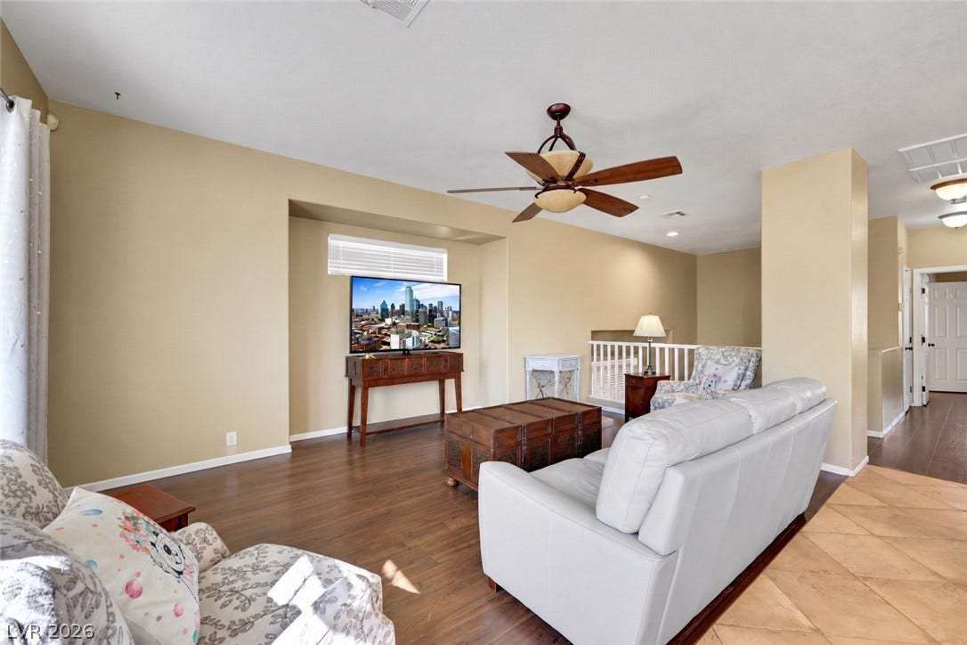 Rich wood floors and a raised ceiling define this upper-level living space. (AI used to remove contents of room).