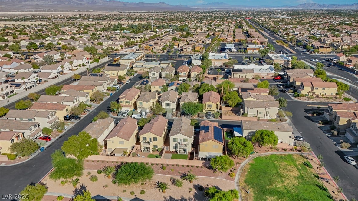 An aerial perspective reveals a serene residential neighborhood bordered by majestic mountain ridges in the distance.
