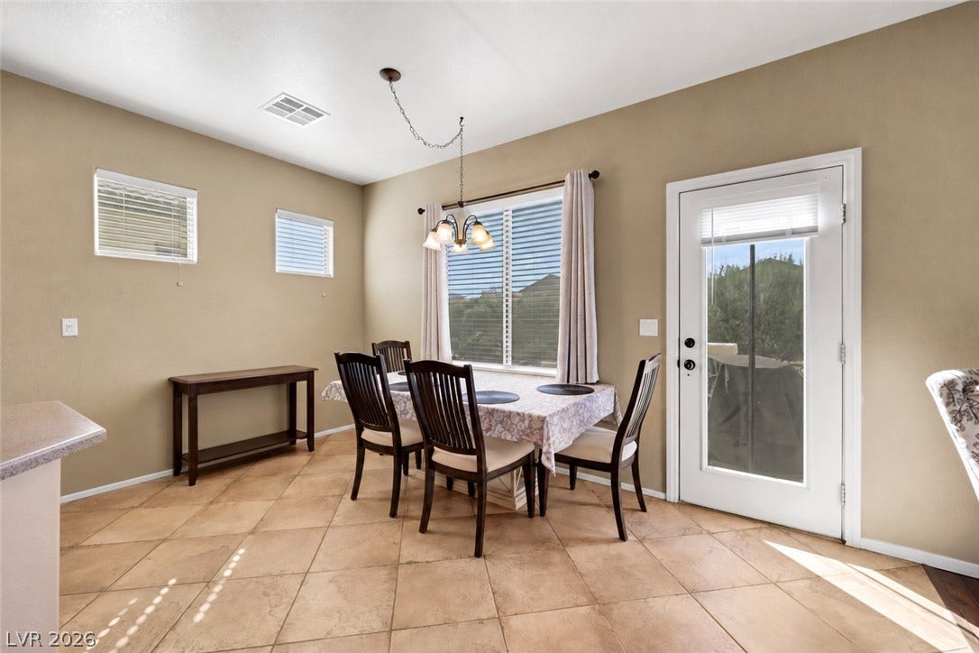Sunlight streams through the glass door onto tiled floors in this charming dining area. (AI used to remove contents of room).