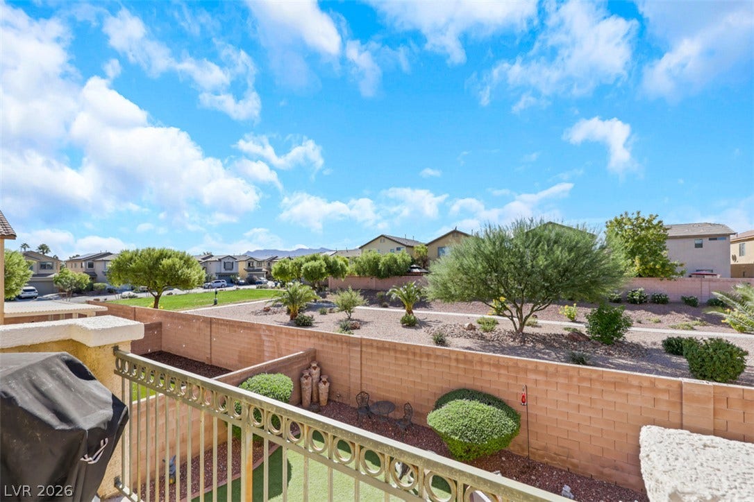 A high-angle view captures the enclosed backyard space and neighboring community landscape under a cloudy sky.