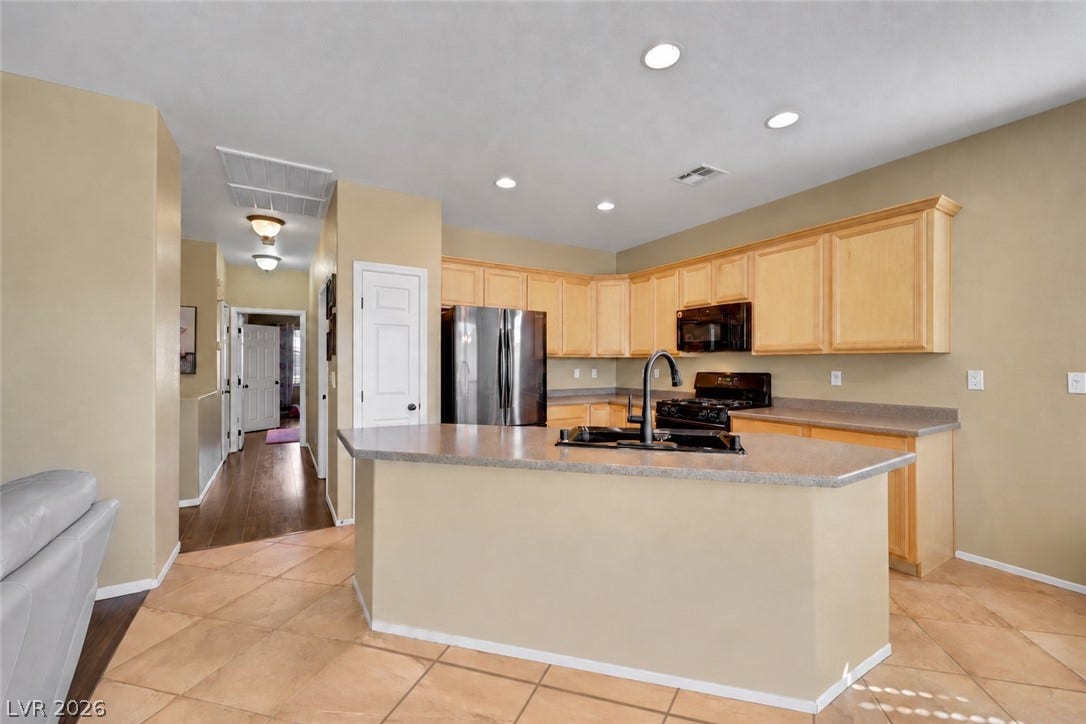 An open kitchen layout transitions smoothly into neighboring hallways over tile and wood like flooring.