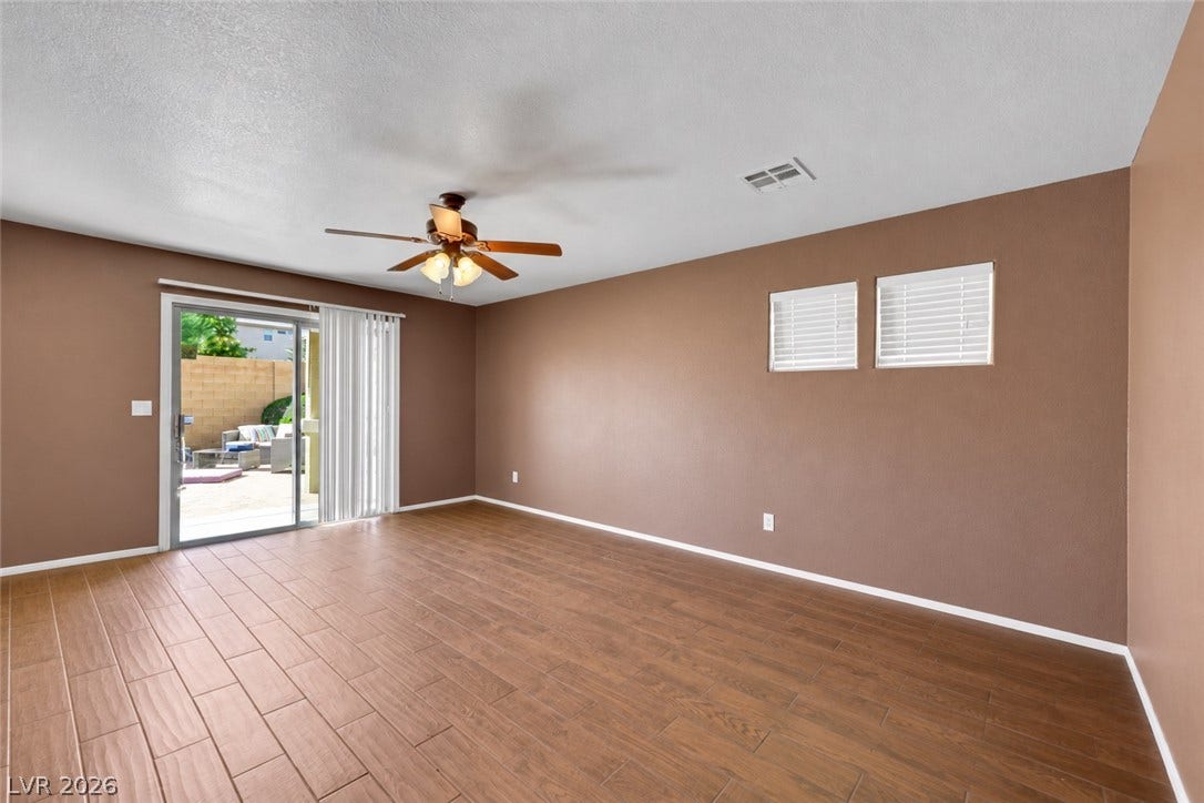 A sliding glass door opens to the patio from this versatile living area/ den. (AI used to remove contents of room)