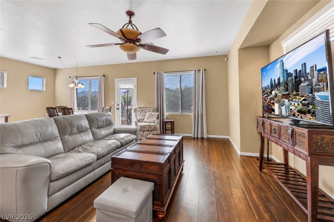 Rich flooring anchors this inviting open living space filled with natural light. (AI used to remove contents of room).