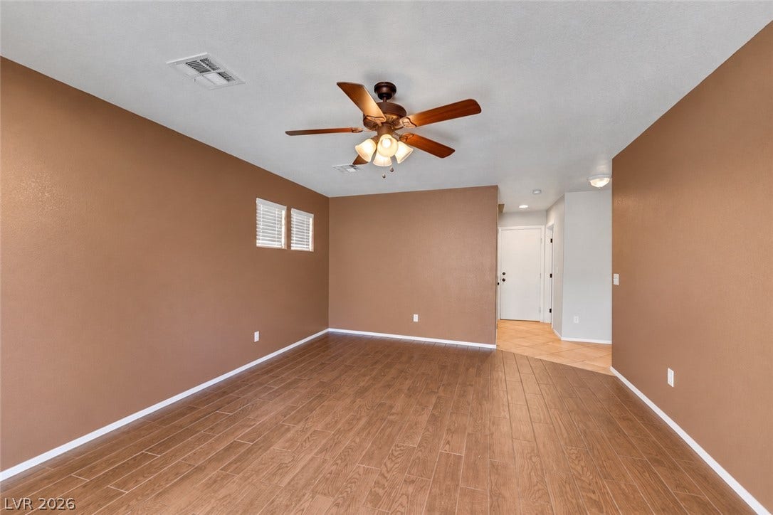 Den with ceiling fan and light looks toward garage door, laundry room, and next to first story bedroom with full bath. (AI used to remove contents of room)