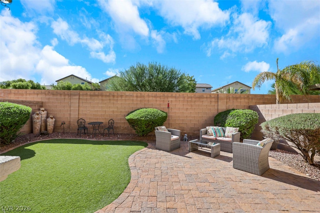 A spacious brick paver patio overlooks the manicured lawn within a private walled yard.