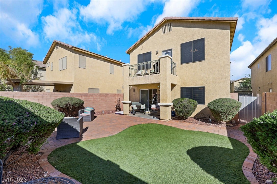 A paved patio and tidy lawn area create a private space behind the residence.