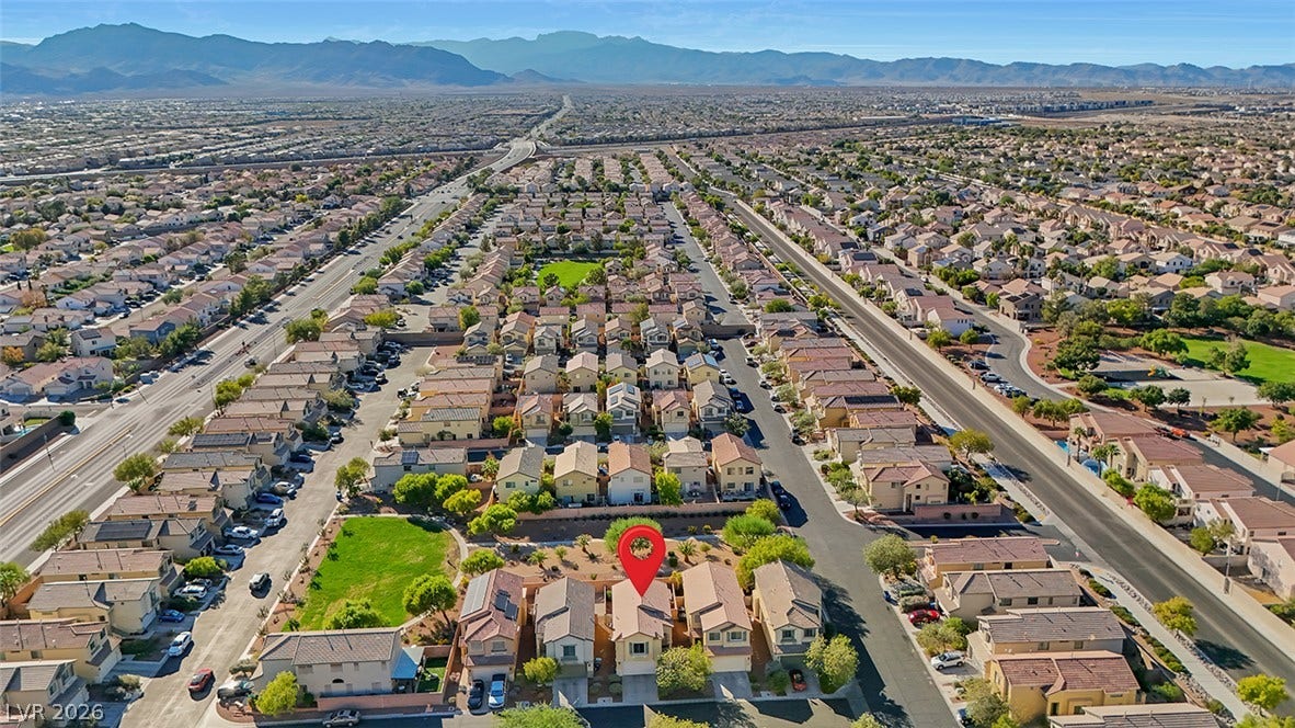 An aerial perspective captures the neighborhood setting with mountain peaks lining the distant horizon.