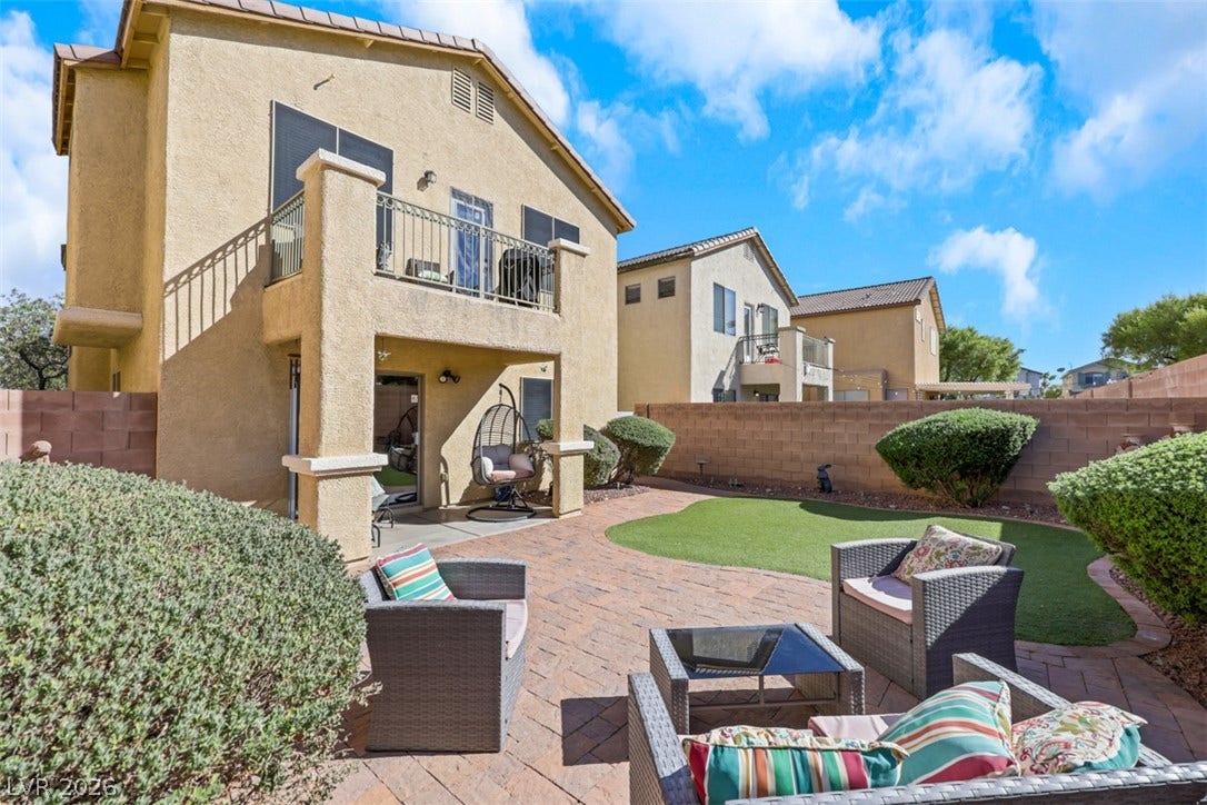 An inviting paver patio extends into a manicured backyard bordered by privacy walls.