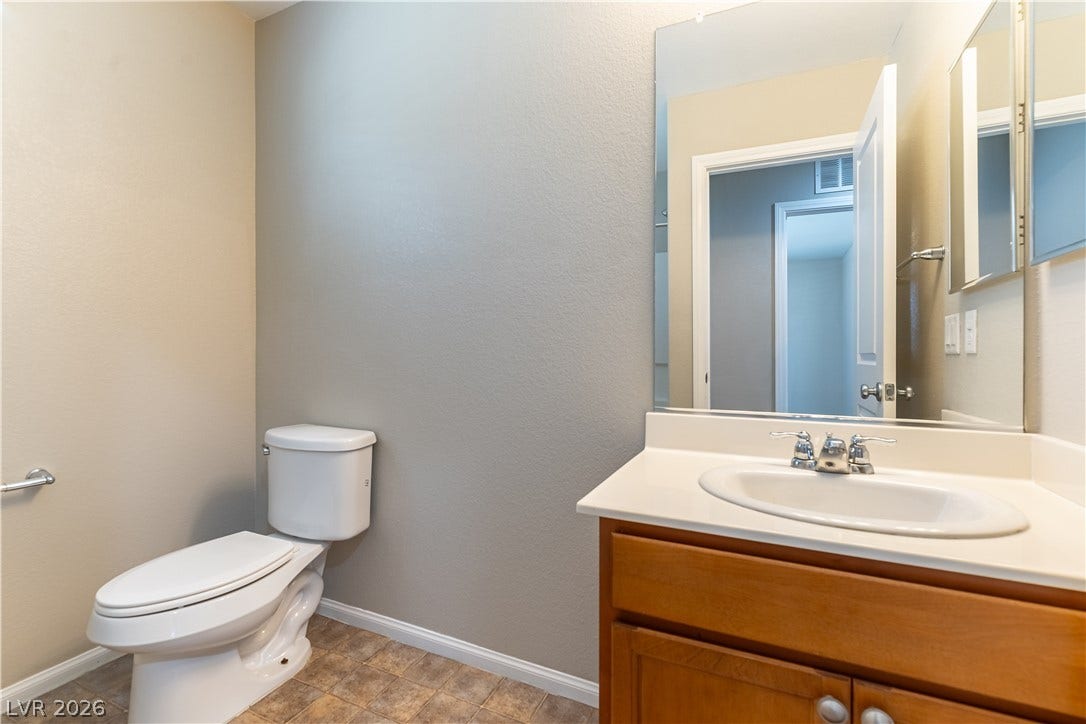 891 Harbor Avenue, Henderson, NV 89002 Warm wood cabinetry pairs with neutral walls in this clean half bathroom.