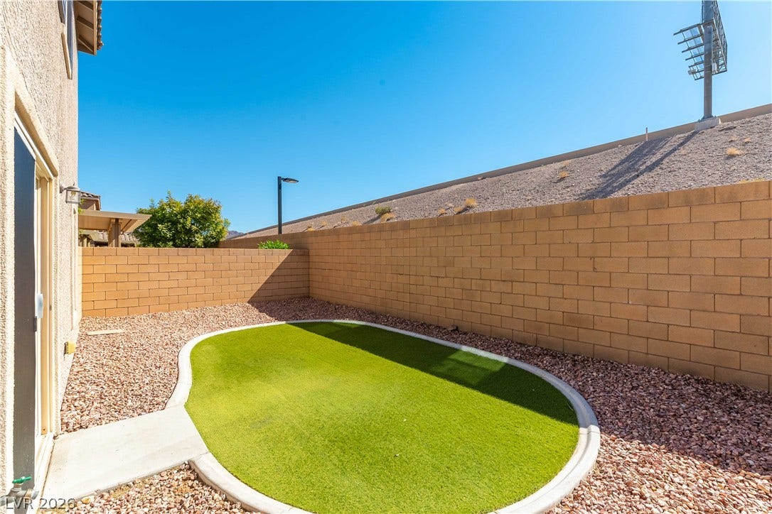 891 Harbor Avenue, Henderson, NV 89002 An enclosed backyard features low-maintenance gravel landscaping and a manicured green lawn area.