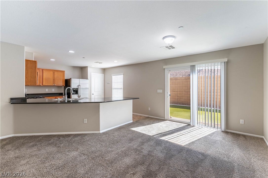891 Harbor Avenue, Henderson, NV 89002 Sliding glass doors open from the carpeted living area to the backyard space.