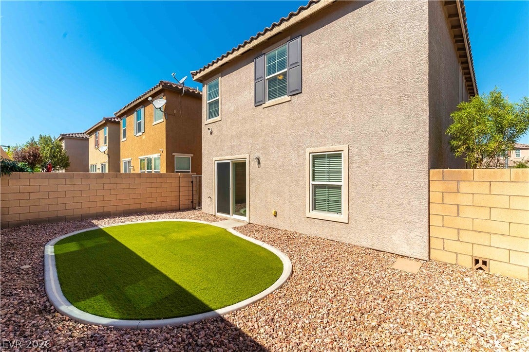 891 Harbor Avenue, Henderson, NV 89002 A low-maintenance gravel yard with a circular green turf insert sits beside the stucco exterior.