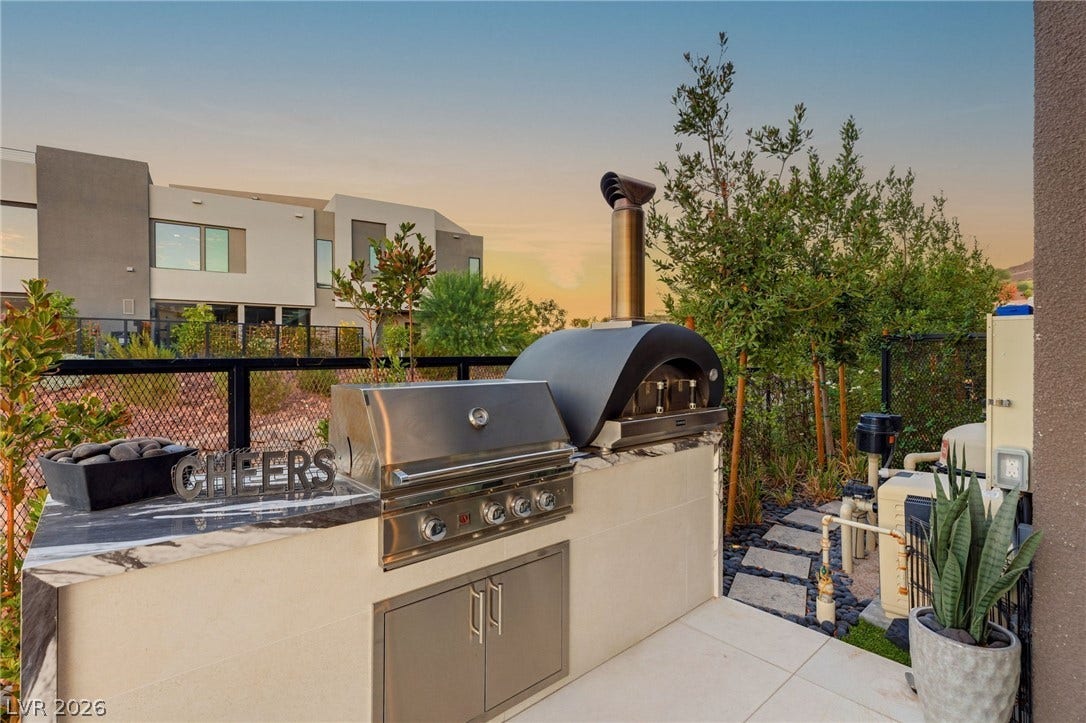 18 Heron Harbour Drive, Henderson, NV 89011 An outdoor kitchen features a built-in gas grill and custom pizza oven setup.