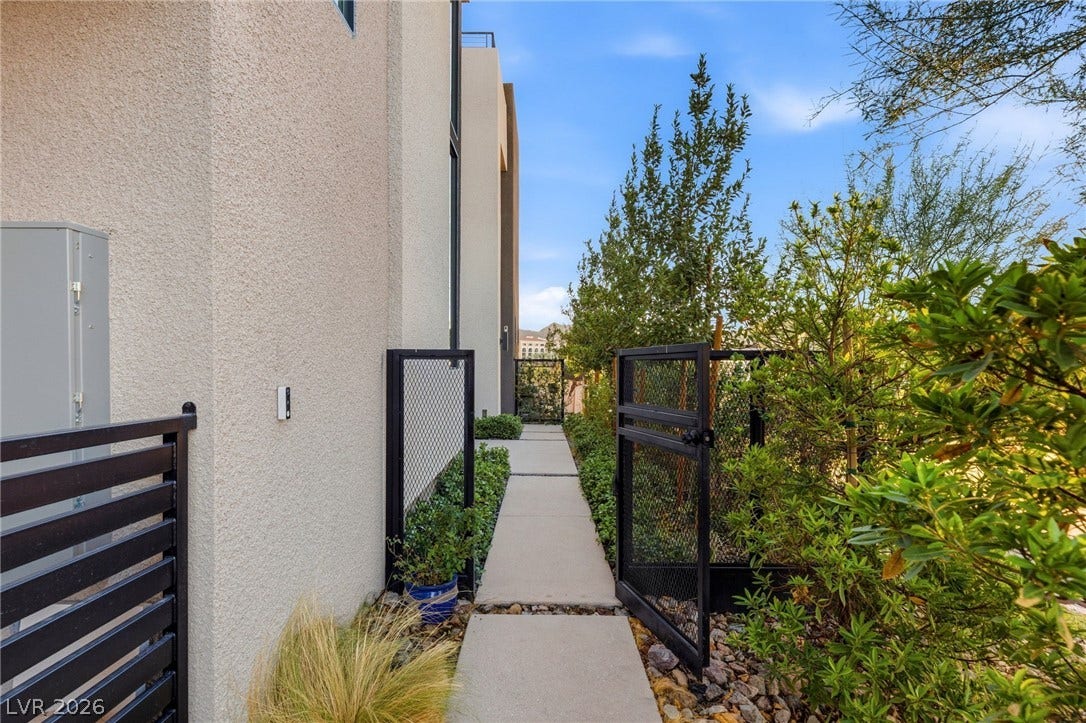 18 Heron Harbour Drive, Henderson, NV 89011 Secure metal gates open to a paved walkway alongside the modern stucco exterior.