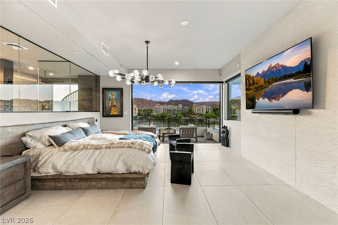 18 Heron Harbour Drive, Henderson, NV 89011 Floor-to-ceiling glass doors open this modern bedroom to sweeping mountain and water views.