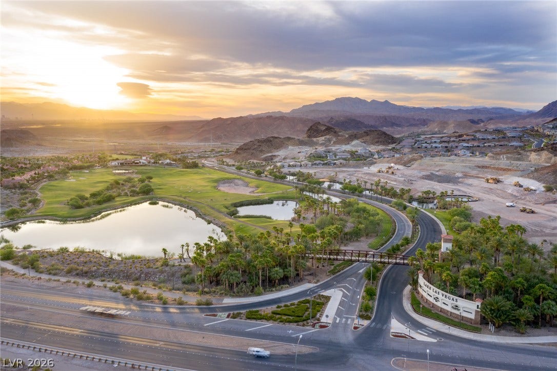18 Heron Harbour Drive, Henderson, NV 89011 Rolling golf course fairways and tranquil lakes nestle against a dramatic mountain backdrop at sunset.